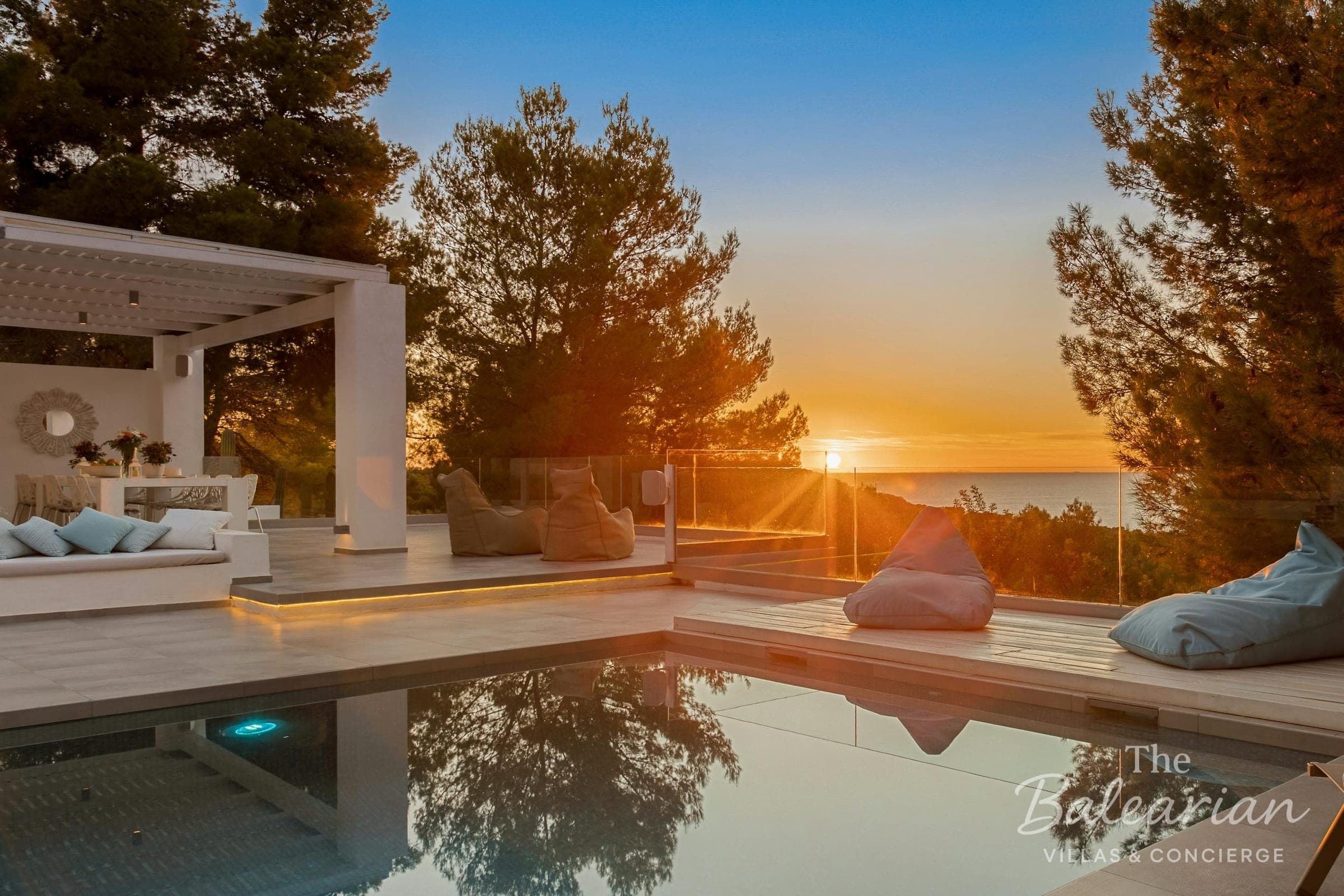 Pool and terrace of a villa at sunset above the sea in Ibiza