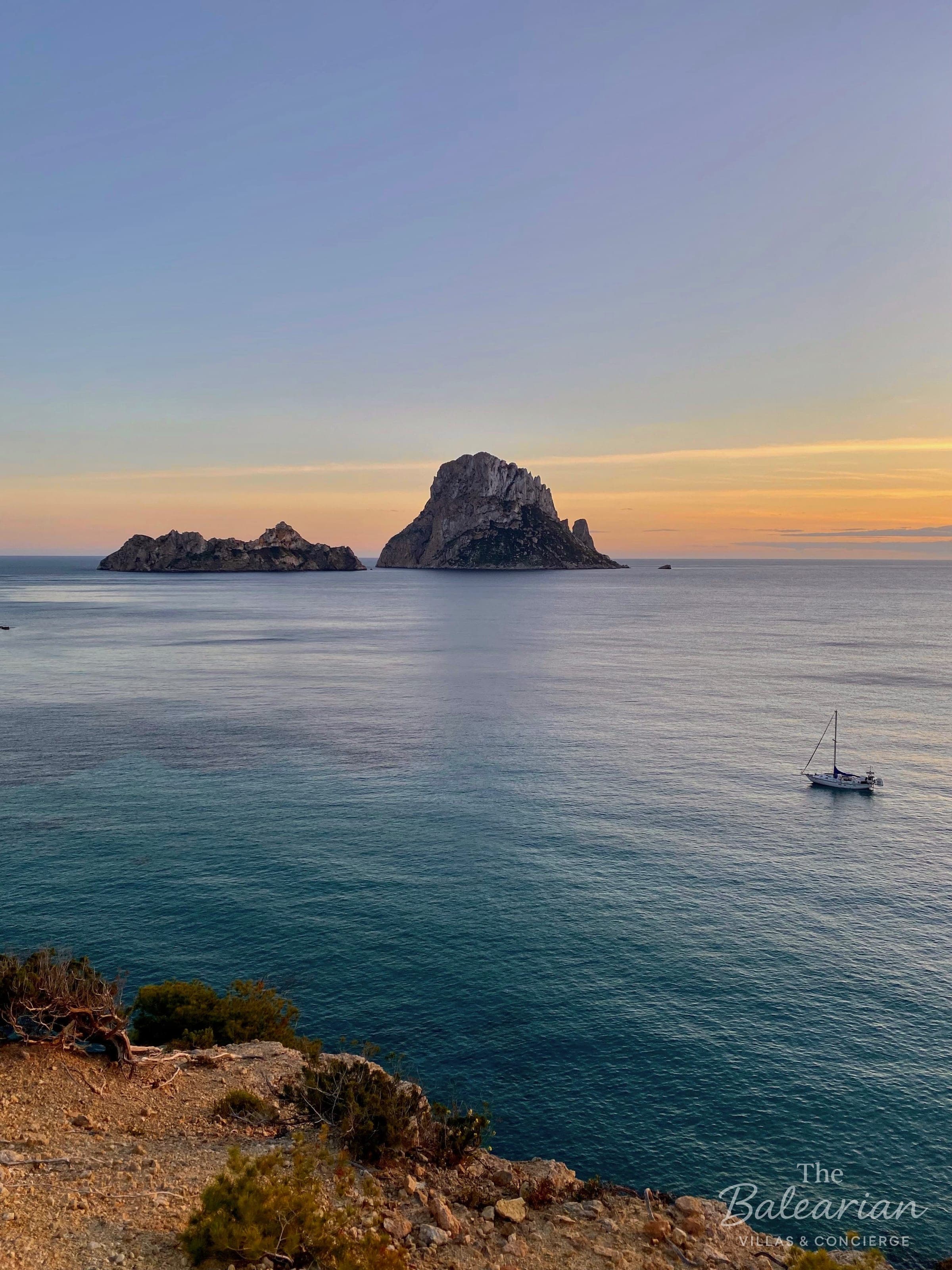 Sailing yacht off Es Vedrà in Ibiza at sunset, concierge service by The Balearian