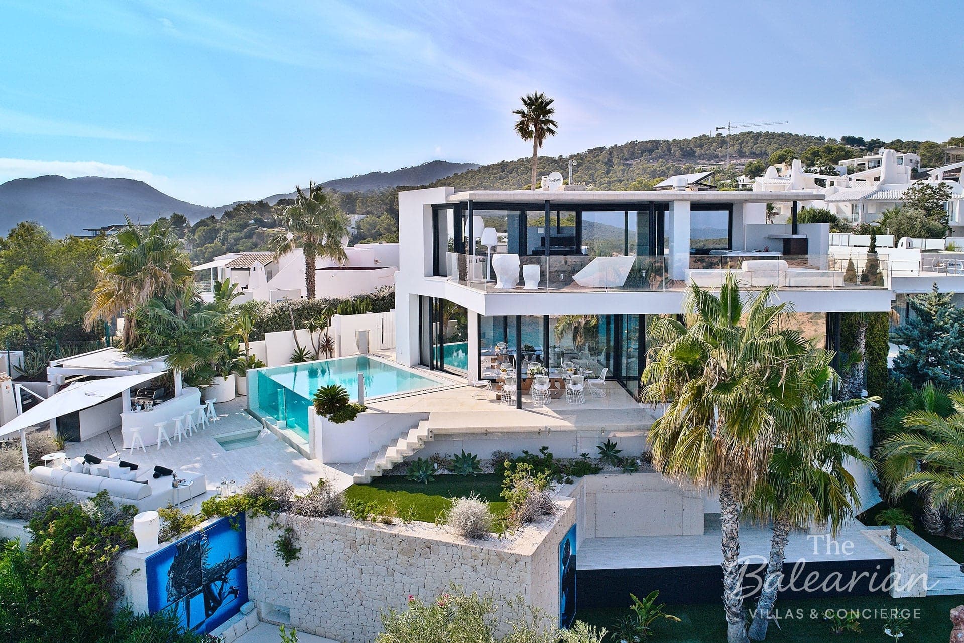 Modern white villa with a pool and palm trees in Ibiza